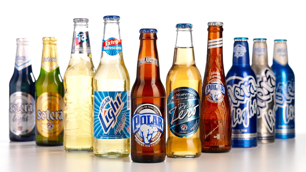 A group of Cervecería Polar beer bottles are lined up on a white surface.