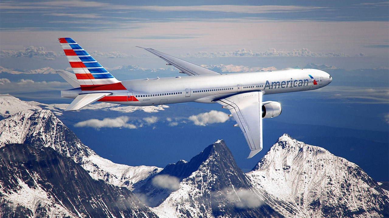 A branded plane soaring over a majestic mountain.