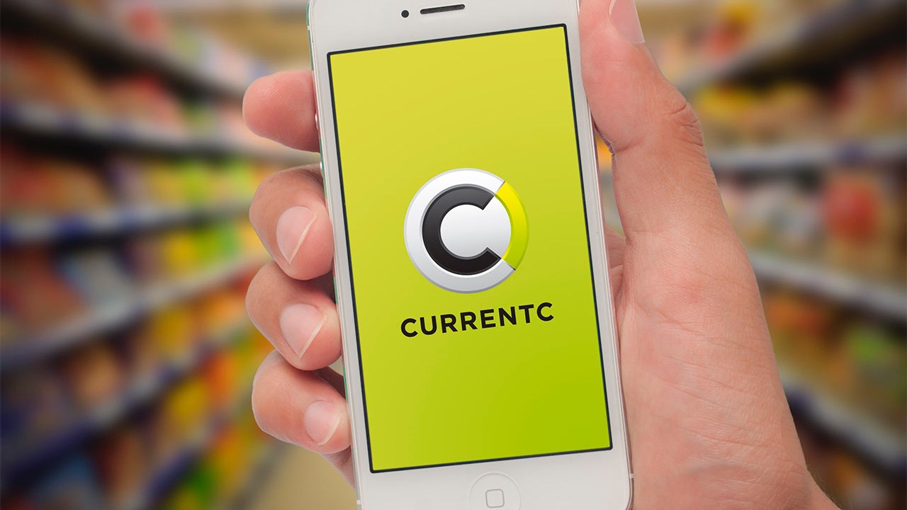 A person is holding up a cell phone with the Currentc logo on it.