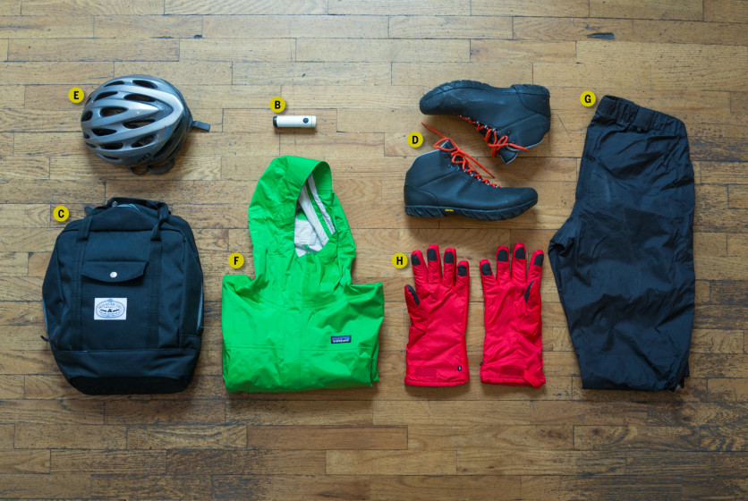A backpack, helmet, gloves, and other items are laid out on a wooden floor.