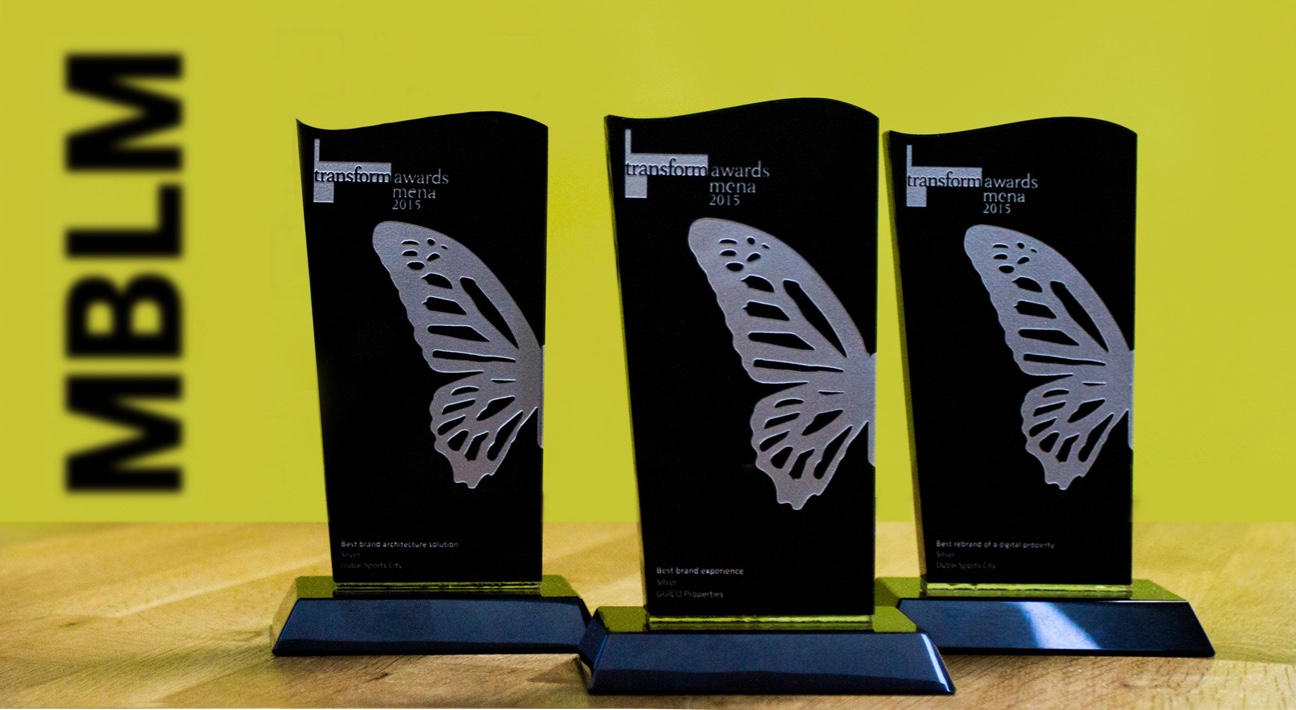 Three butterfly shaped awards on a wooden table.