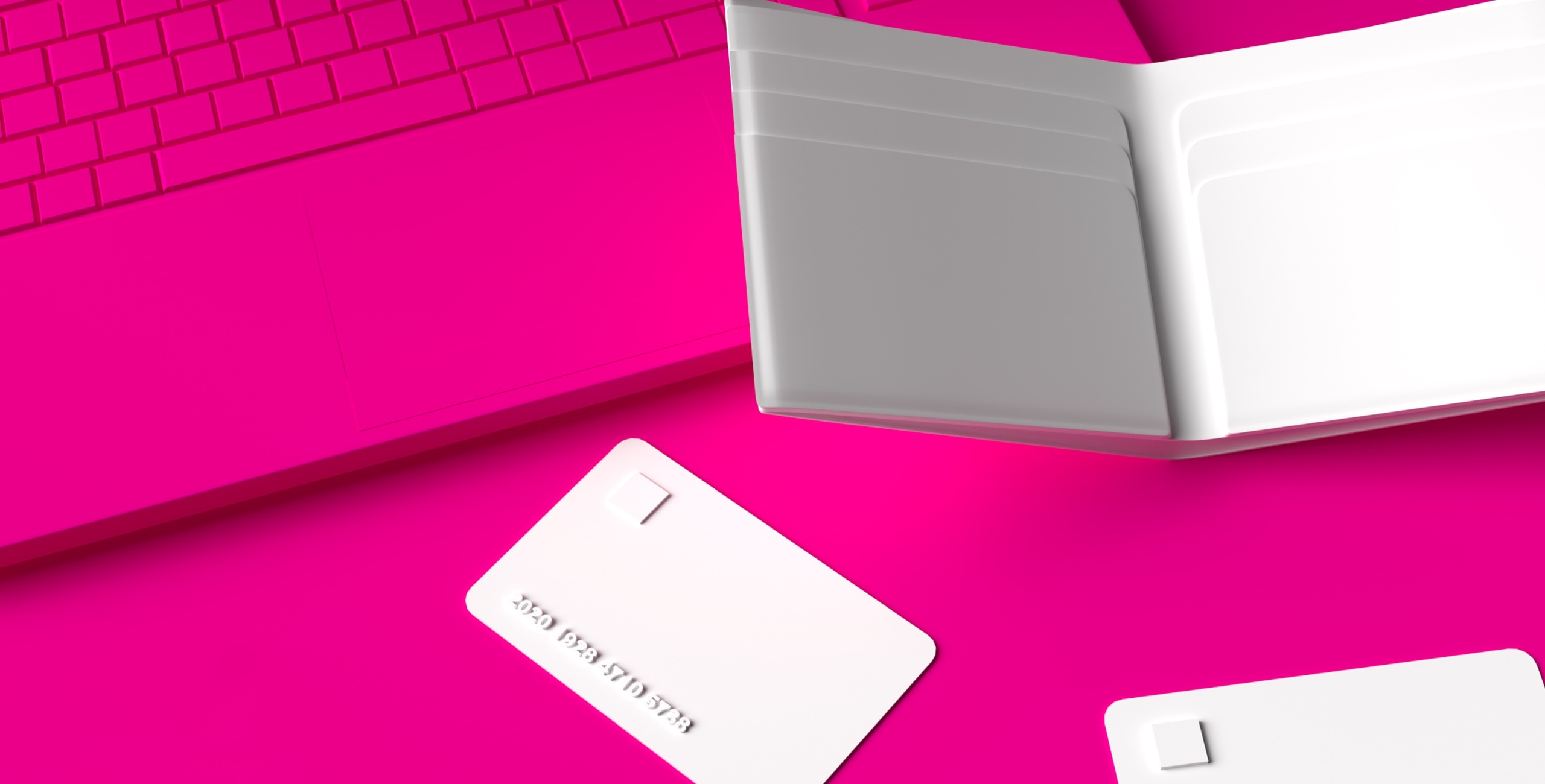 A laptop on a pink background with a white book and credit cards.