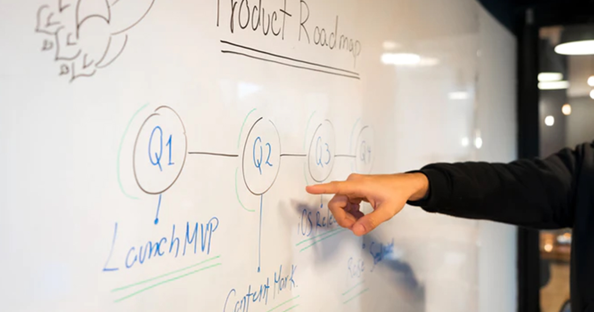 A man pointing to a whiteboard with a diagram on it.
