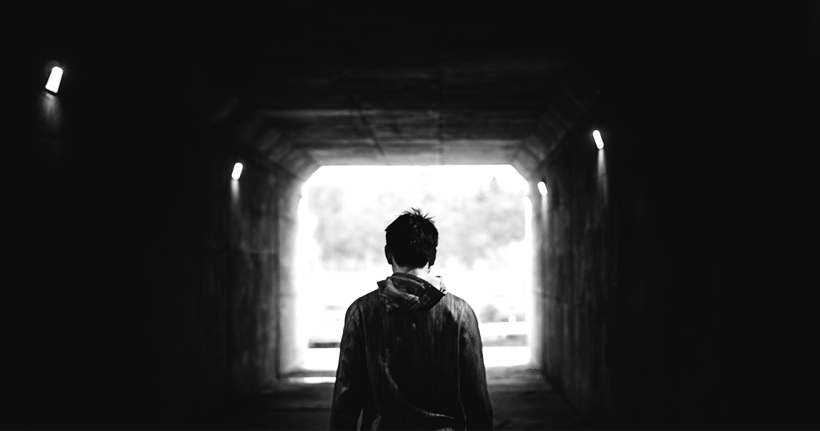 A black and white photo of a person standing in a tunnel.