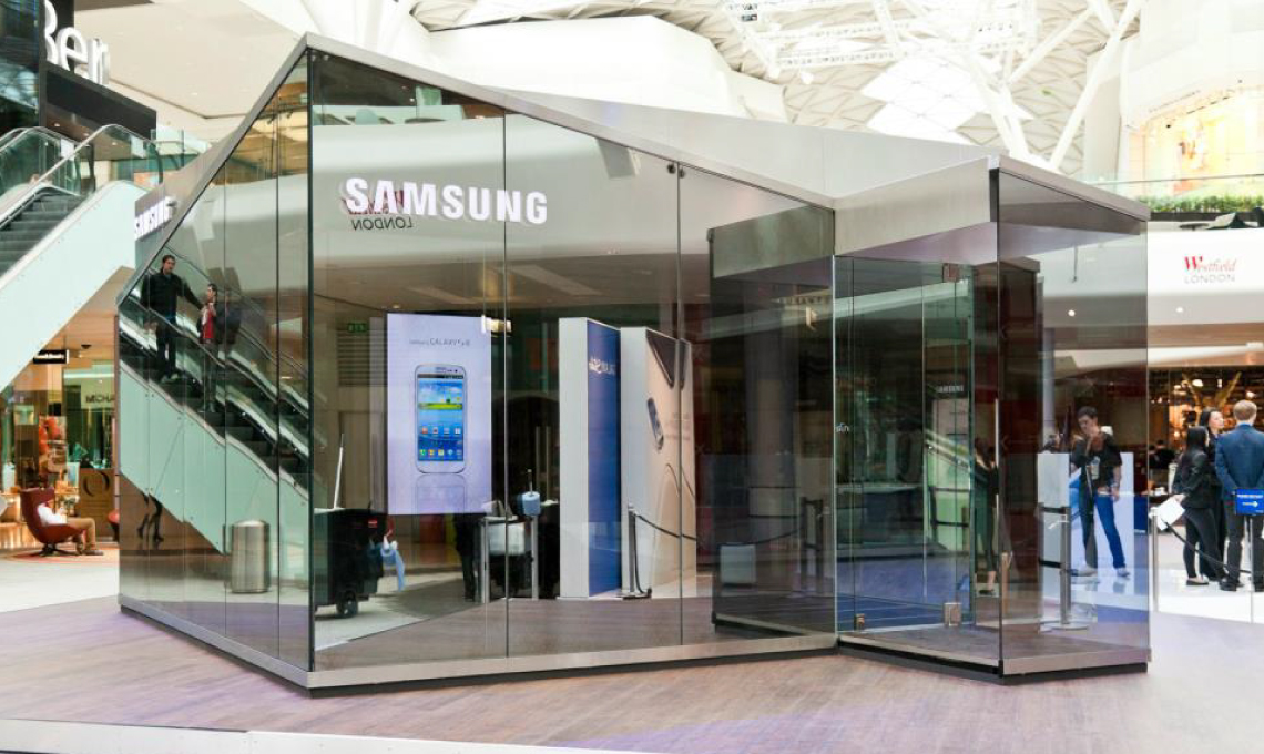 a prototype of the a cell phone sitting next to a prototype of the Samsung Mobile PIN shop