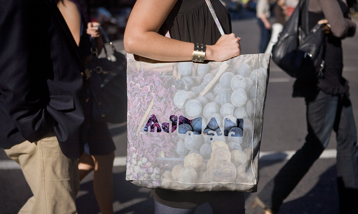 A woman is carrying a tote bag with a picture of grapes on it.