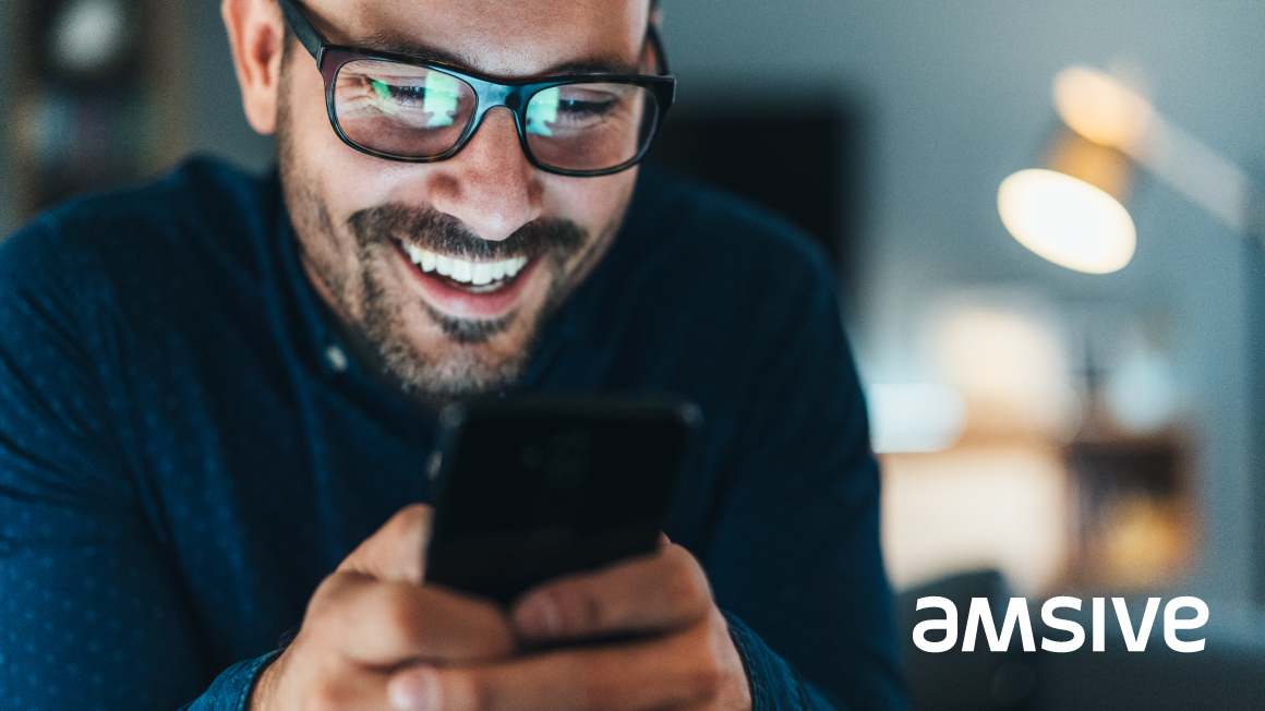 a man with glasses looking at his cell phone with the Rebranding of Amsive, a marketing services agency