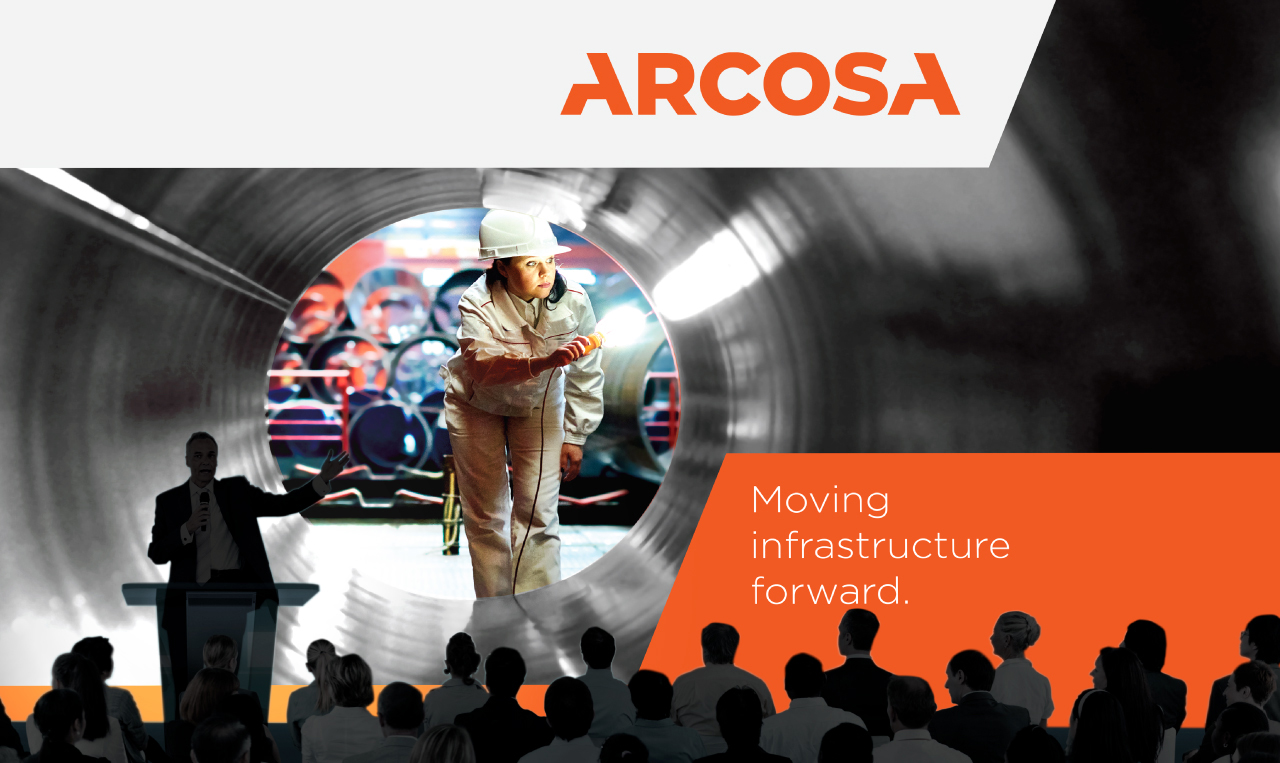a man standing on a stage in front of a crowd with the Arcosa brand in the background
