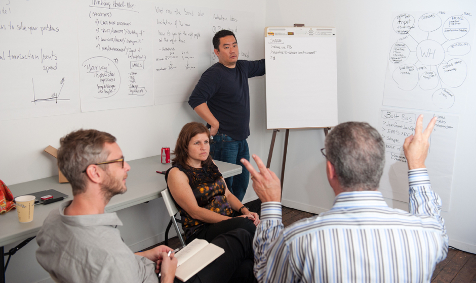 A group of people engaged in content planning, sitting around a whiteboard.