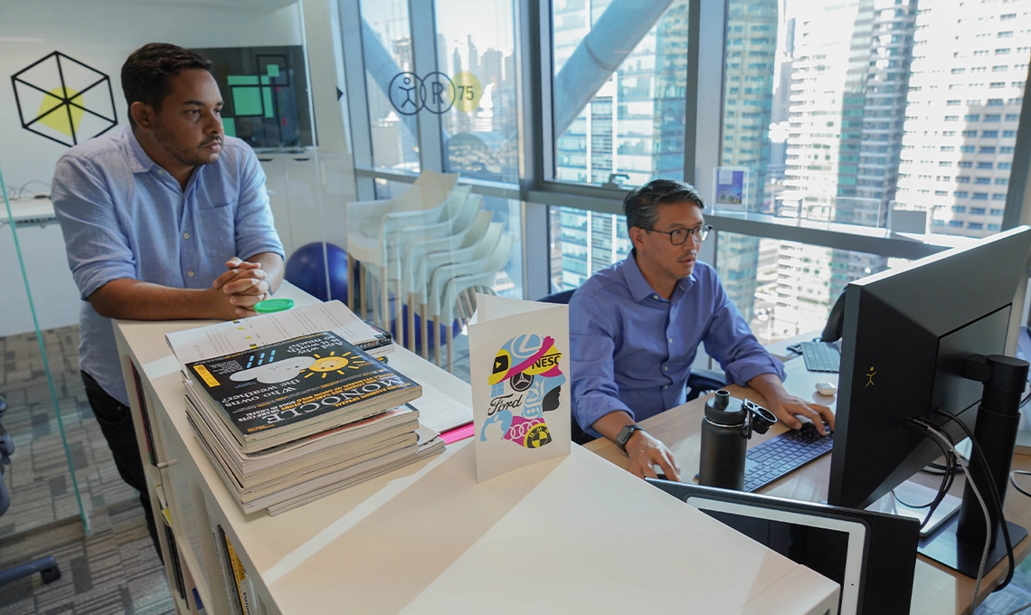 Two men standing in Dubai office looking at a computer