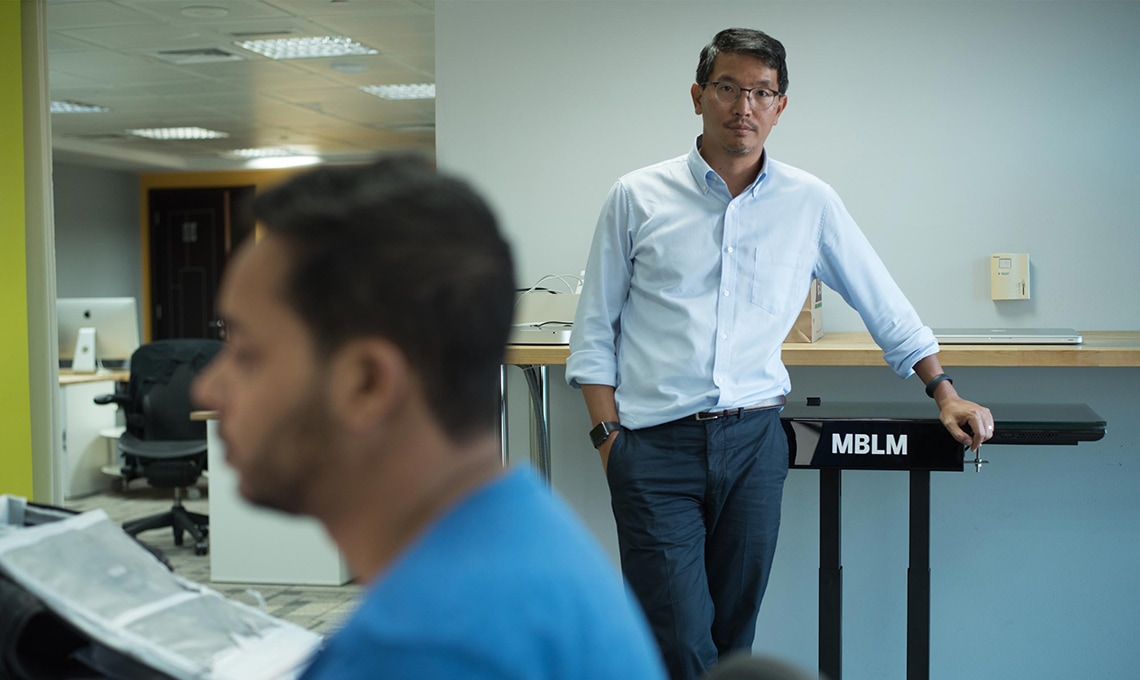William Shintani, Managing Partner, standing in front of a desk in Dubai office