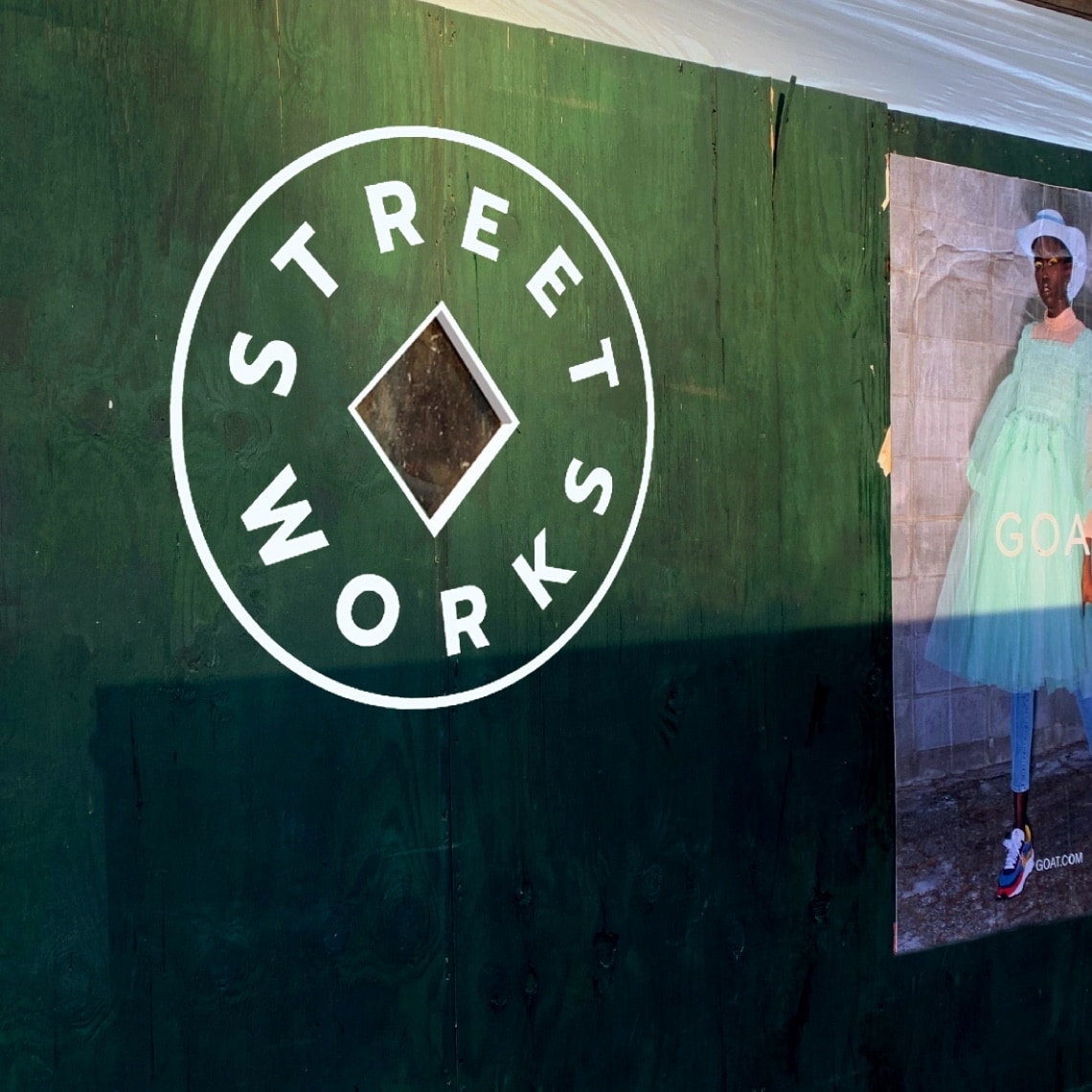 A green wall with the image of a woman and the Street Works logo applied to it