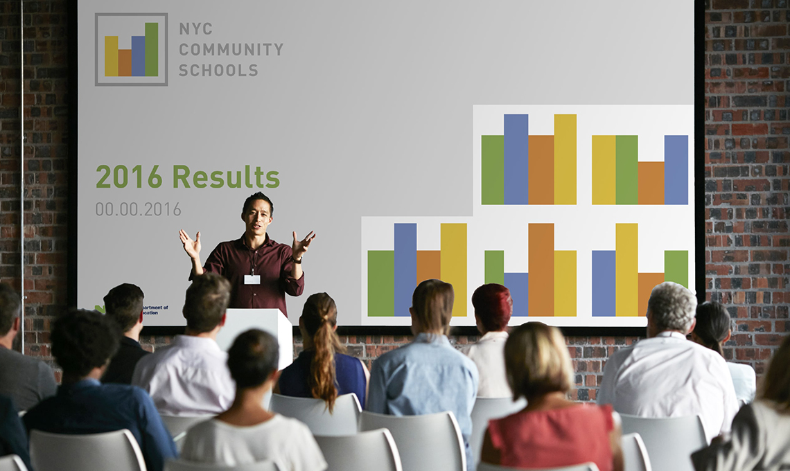 A group of people in front of a screen showing the results of a community school.