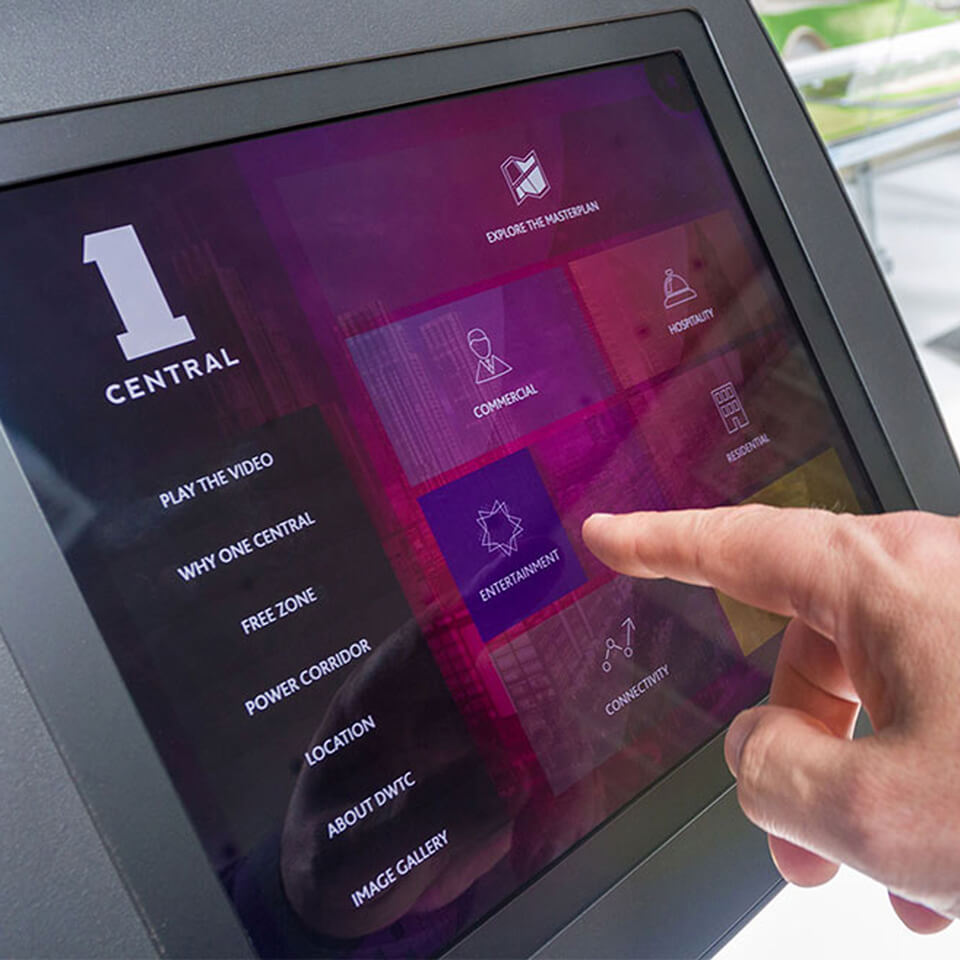 a person pointing at a touch screen showing the presentation developed for One Central