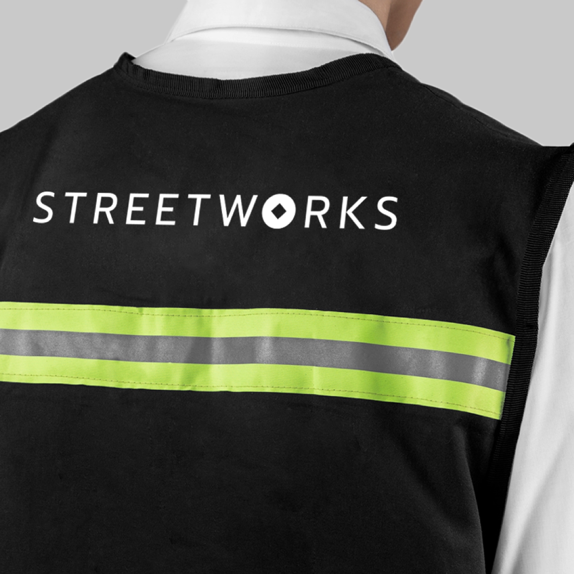 a man wearing a black vest with neon stripes and the logo of street works in white