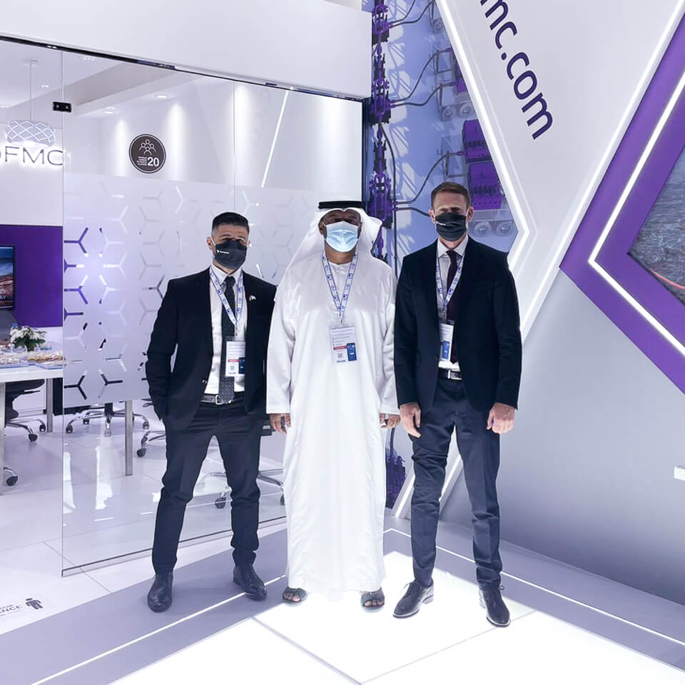 a group of three people standing in a TechnipFMC showroom