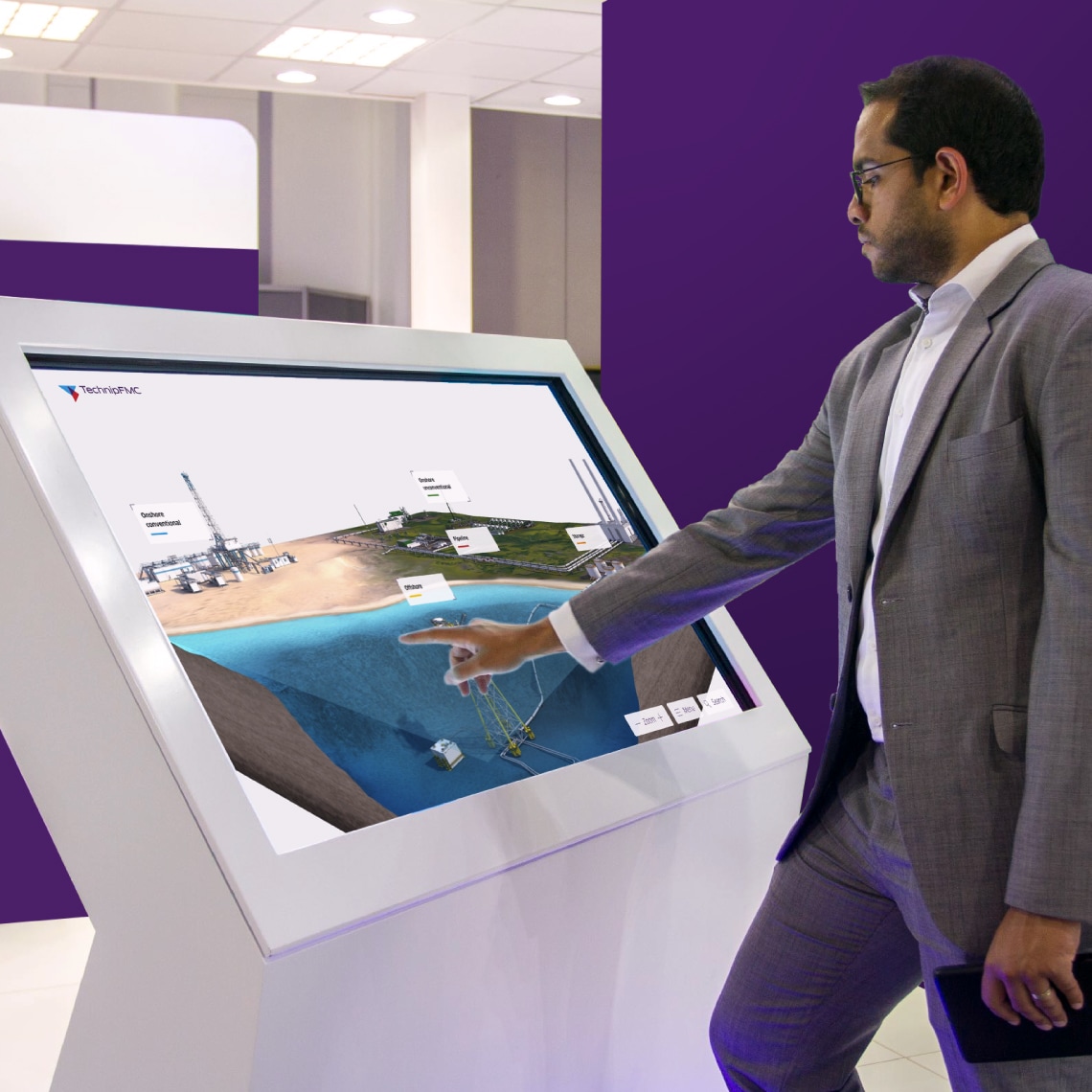 a person pointing at a touch screen showing the presentation developed for TechnipFMC
