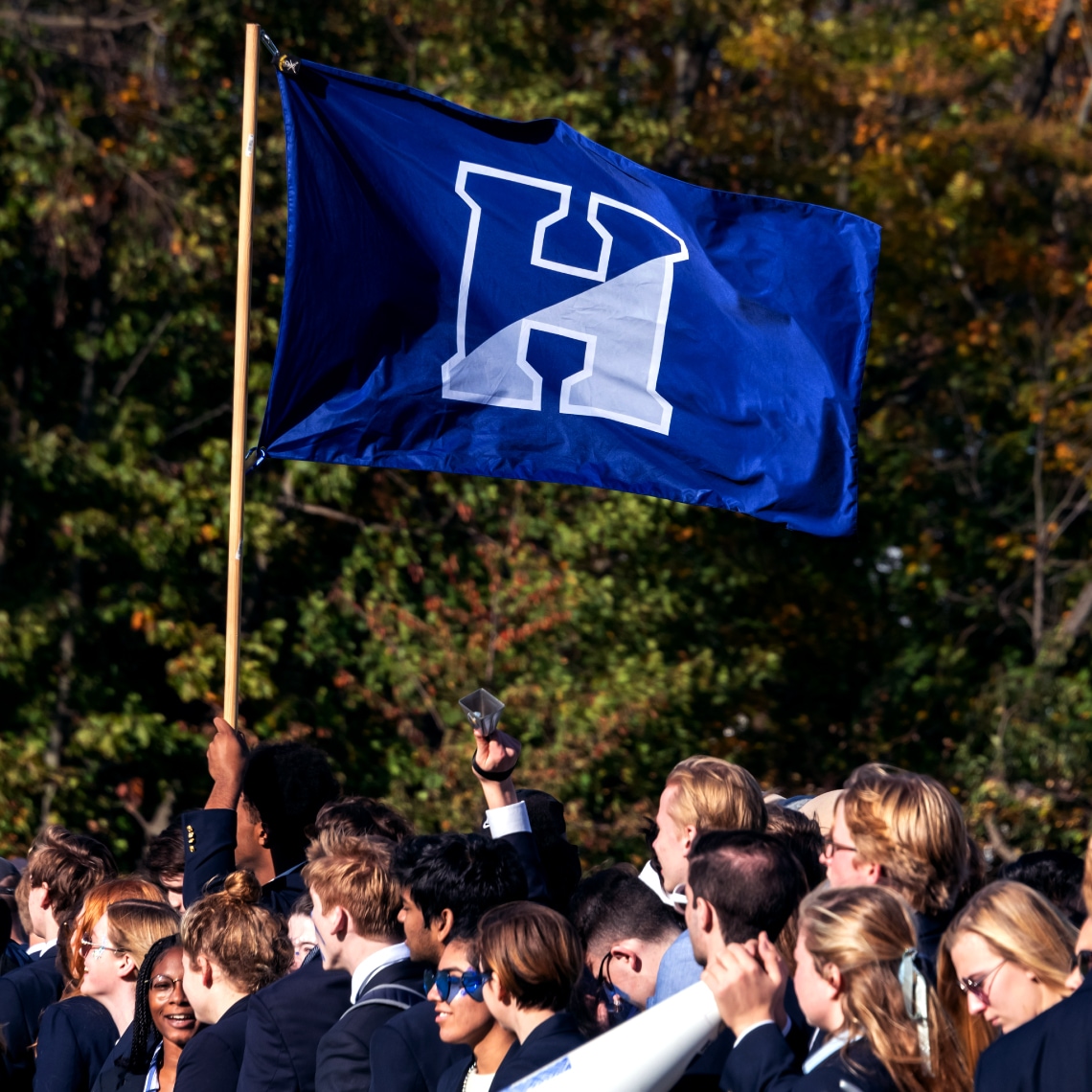 a group of younf students holding a blue flag with the Athletic Logo