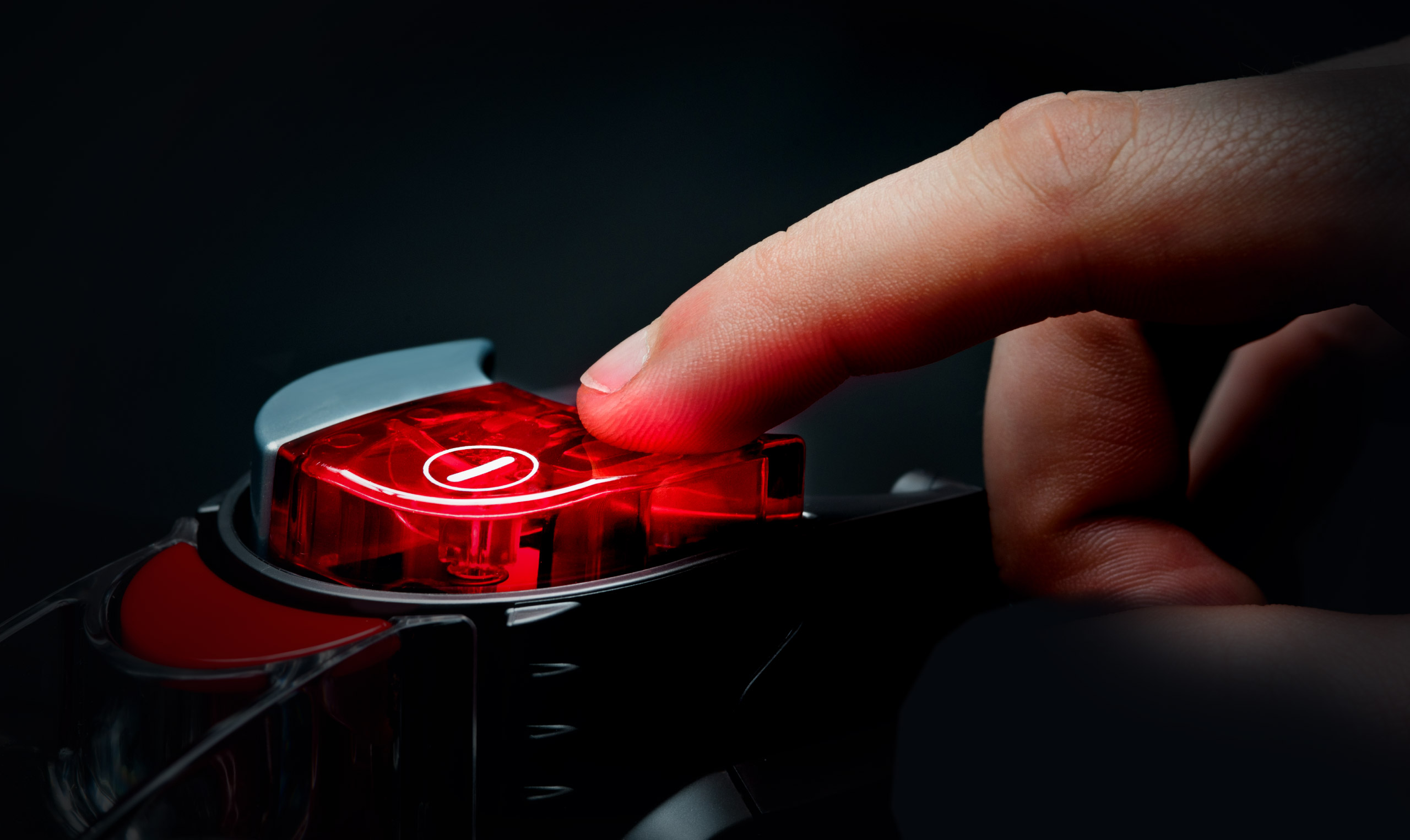 A person's hand is pressing a red button.