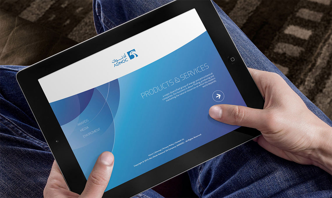 A man with a tablet in his hands showing the website developed for ADNOC