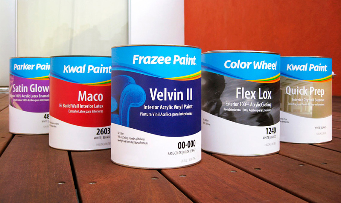 a group of cans of paint with the new brand identity developed for Comex, sitting on a wooden table.