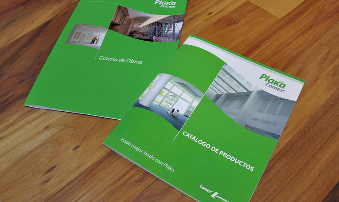 Two green Plaka brochures on a wooden floor.