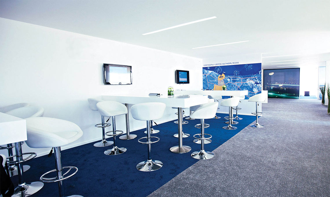 A blue carpet in a room with white bar stools for market reentry.