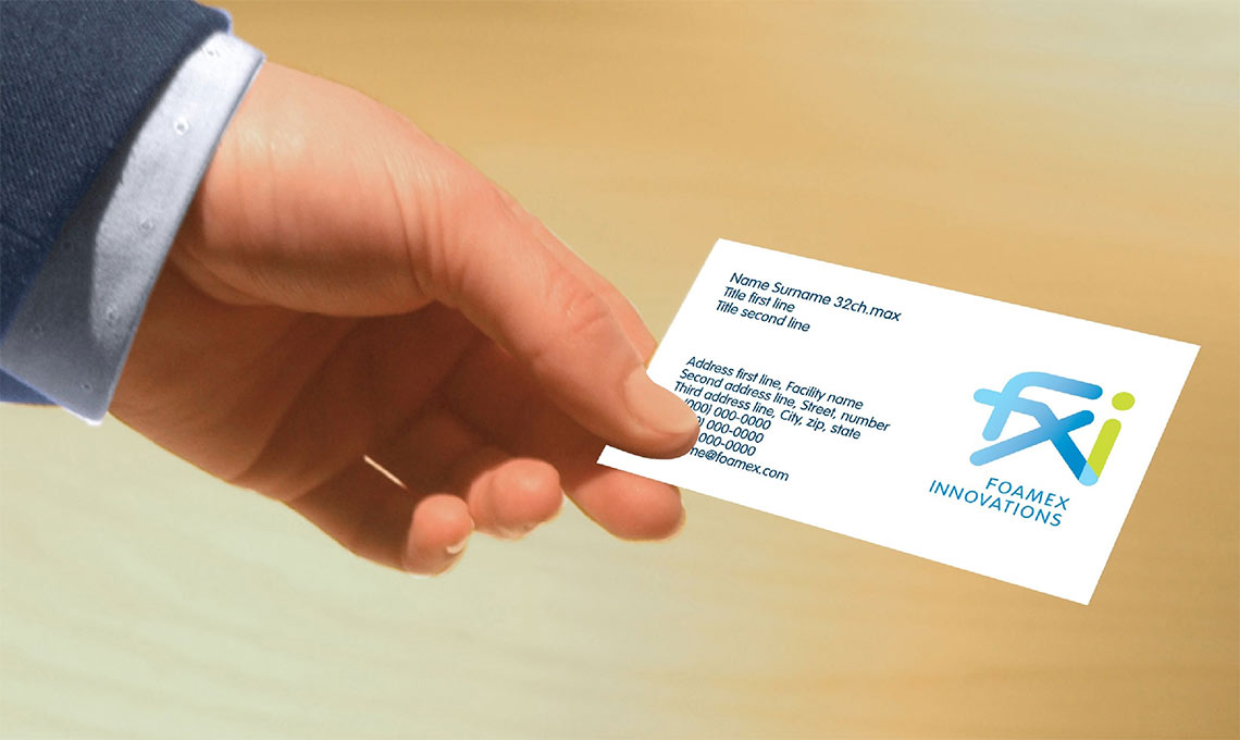 A man's hand holds an example of a business card developed for FXI.