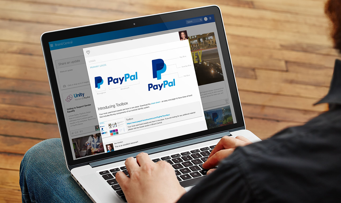 A person using a laptop with the paypal logo on it.