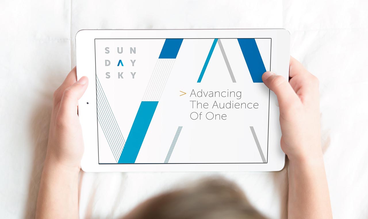 A woman holding an iPad with the title Sunday Sky introducing a brand program to the audiences.
