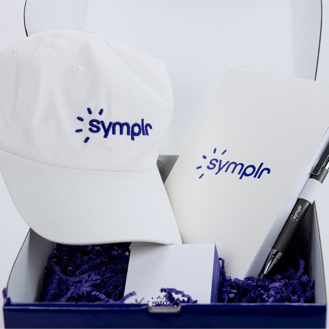 Examples of a gift box with Marketing materials including swag items like baseball caps, pens, and notepads