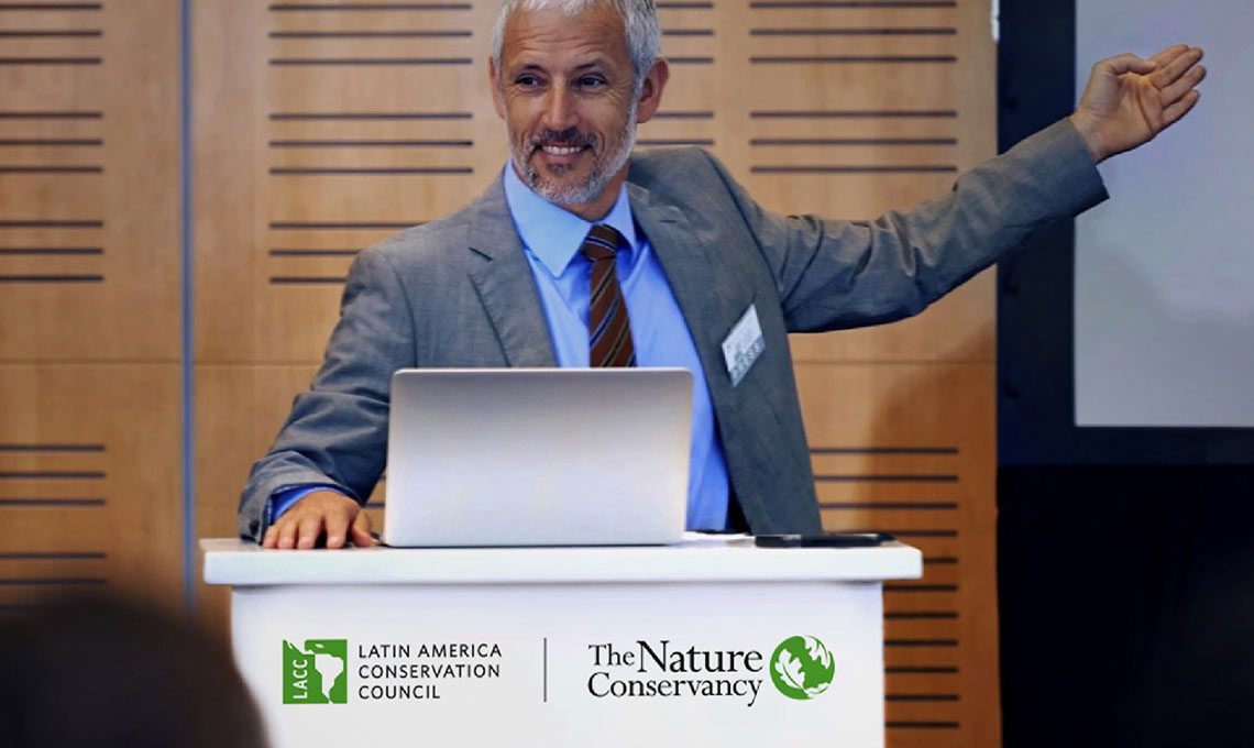 a man in a suit behind a podium with the logo of The Nature Conservancy giving a presentation