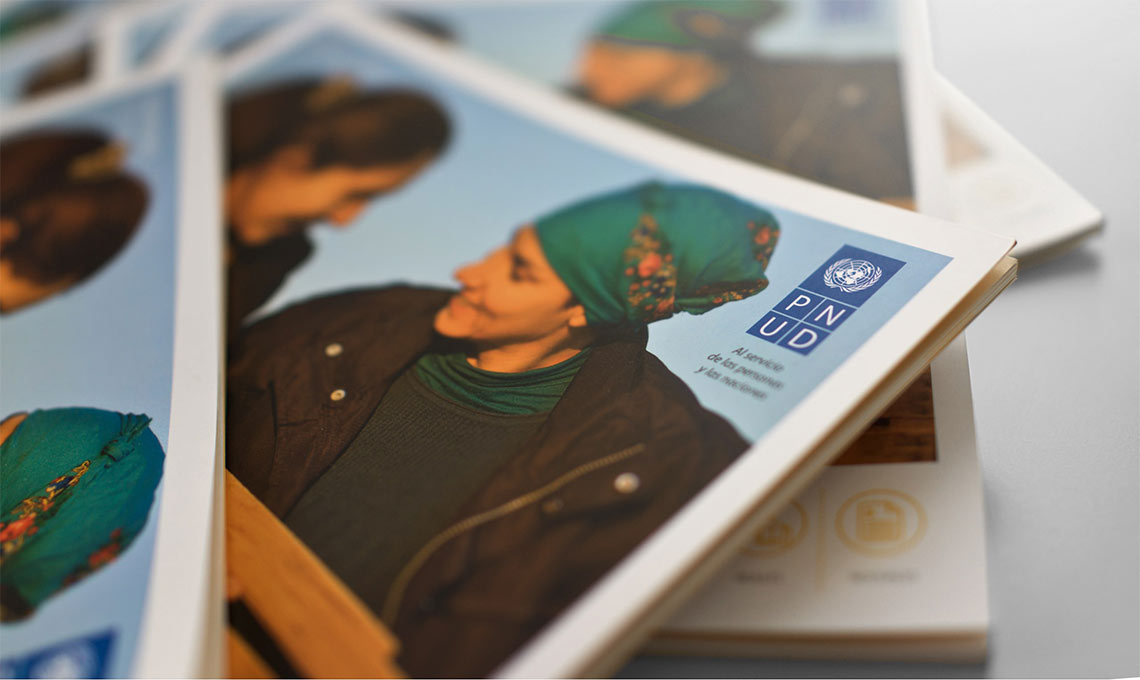 A stack of magazines featuring a woman wearing a hat promoting the United Nations Development Programme.