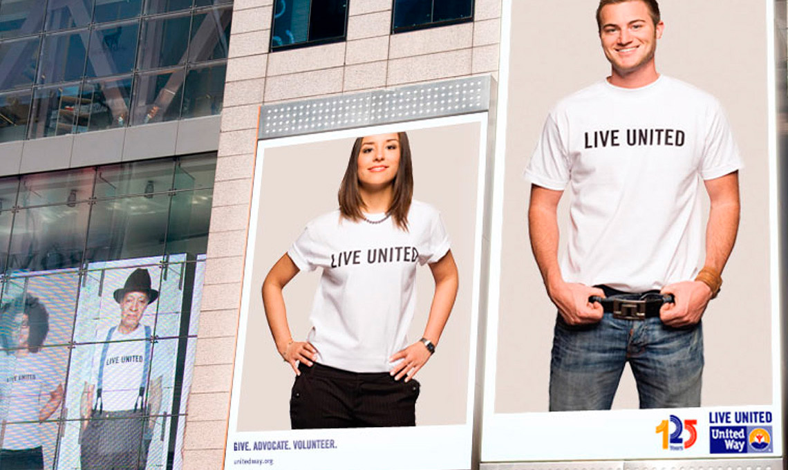 Two people standing in front of a building with t - shirts that say live united.