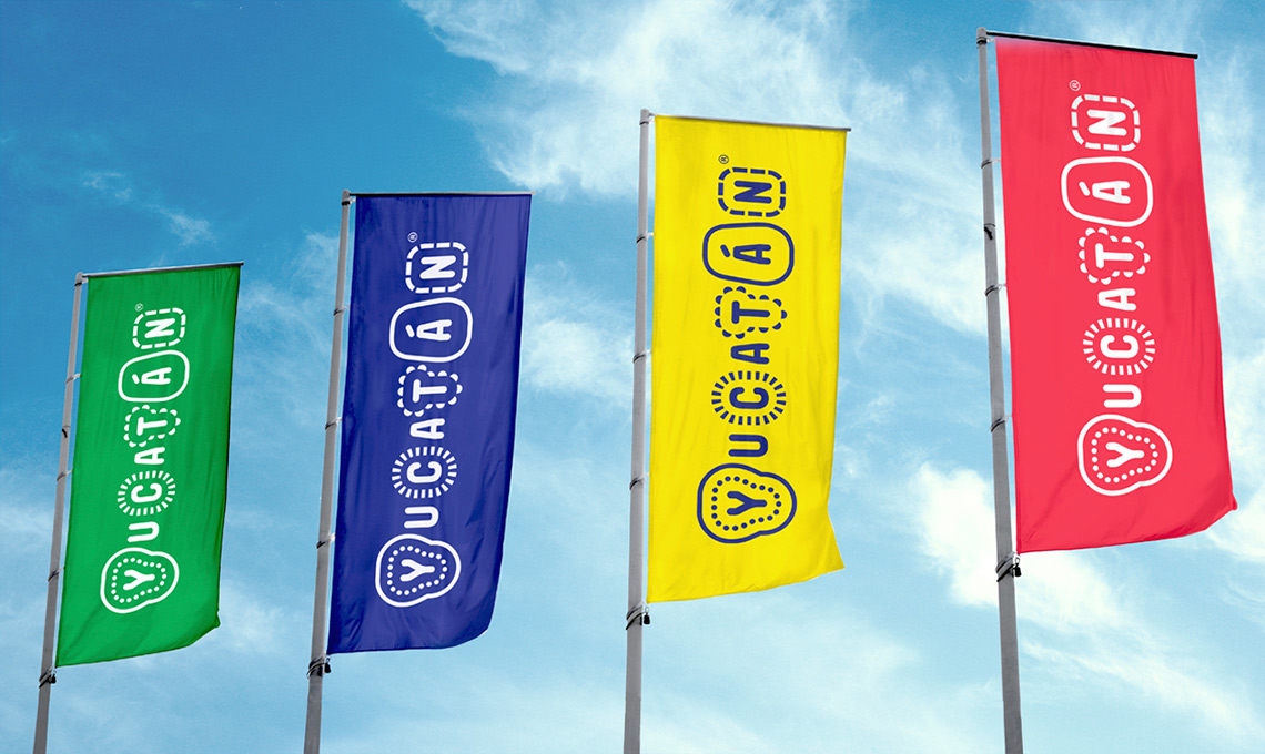 A group of flags displaying destination branding on a pole in front of a blue sky.