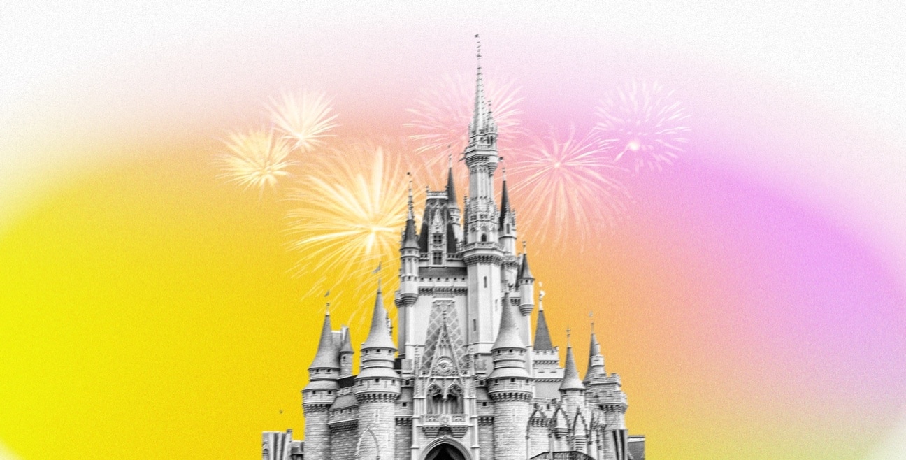 The top of Cinderella Castle with fireworks over a yellow and pink gradient