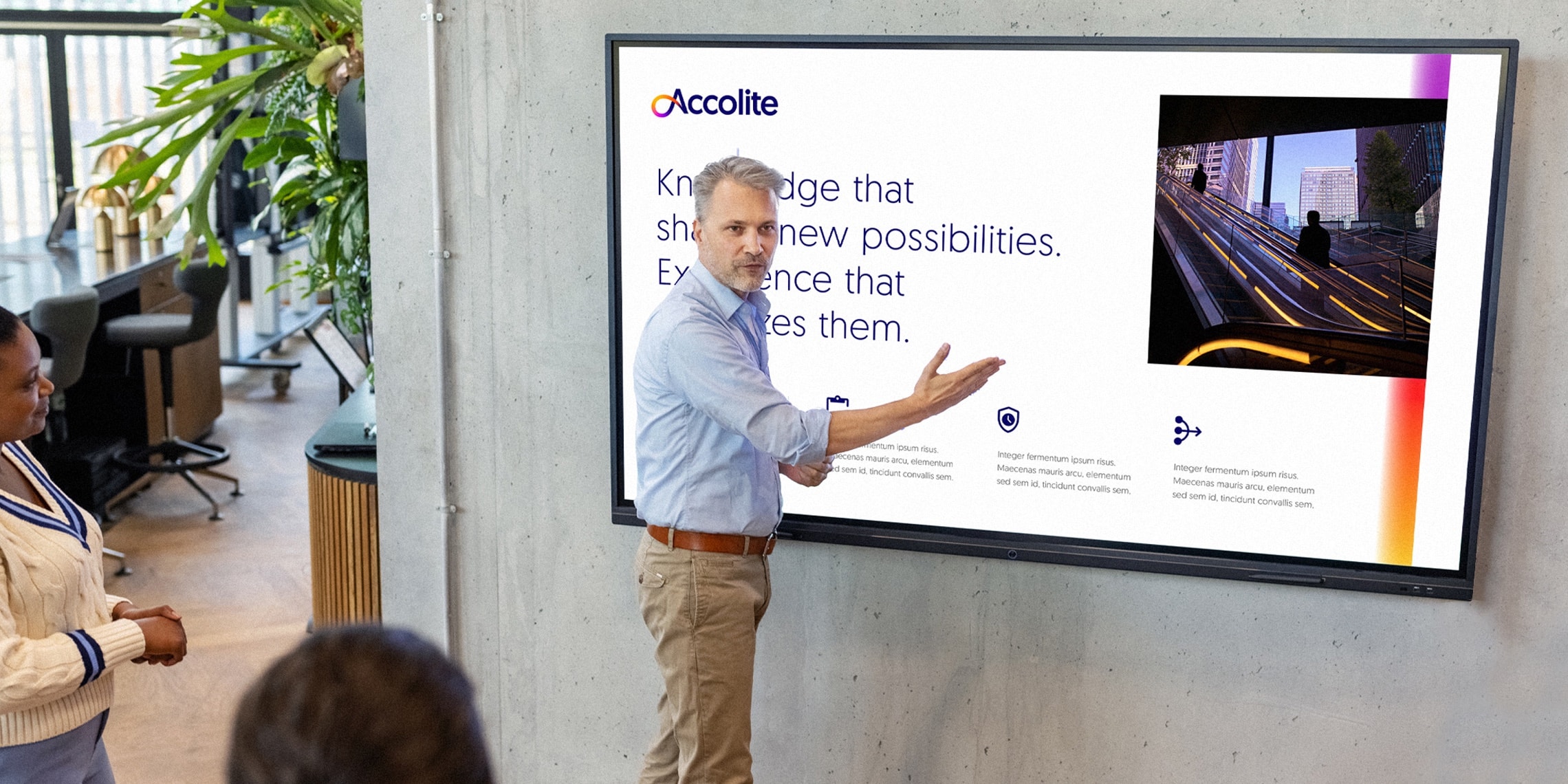 A man in front of a large screen displaying an Accolite presentation