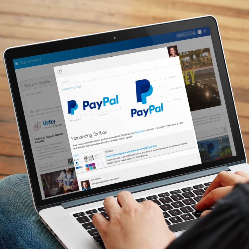 A person using a laptop with the paypal logo on it.