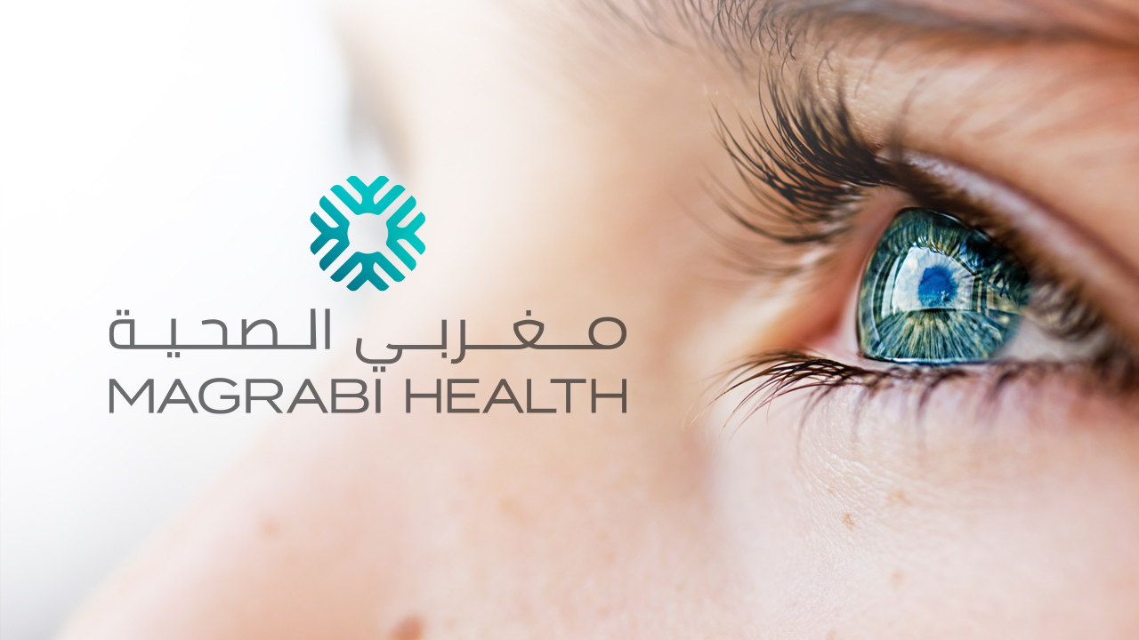 The Magrabi health logo with the watermark symbol, designed by MBLM over a close up image of a person’s eye honoring the brand’s ophthalmology legacy.