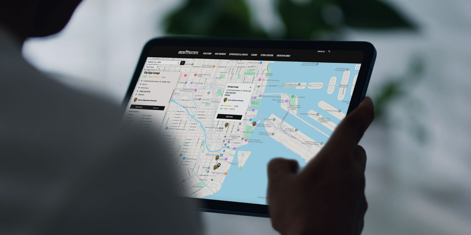 Person holding a tablet displaying a digital map of a city waterfront area with various locations and routes marked on the screen.