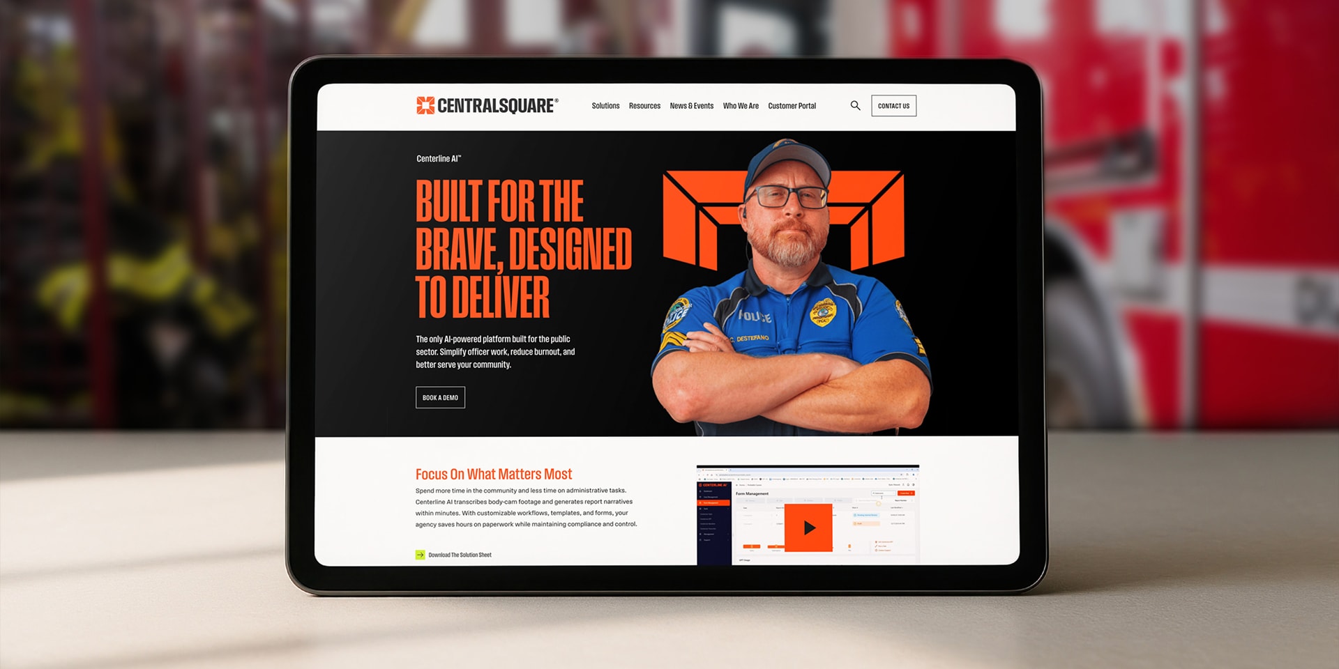A tablet displays the CentralSquare website, featuring a uniformed man with folded arms and the text “Built for the Brave, Designed to Deliver.”.