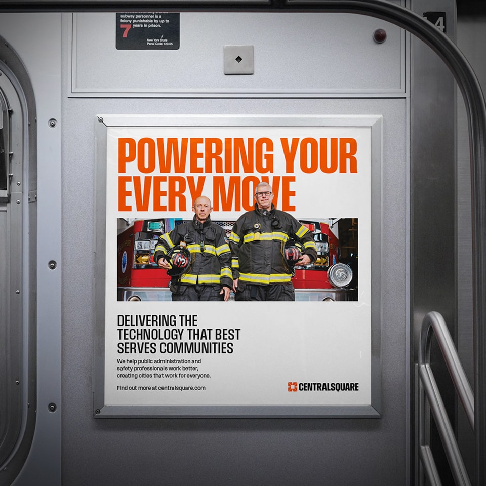 Subway ad showing two firefighters in uniform holding helmets, standing in front of a fire truck. The text reads, "Powering Your Every Move" and promotes CentralSquare technology.