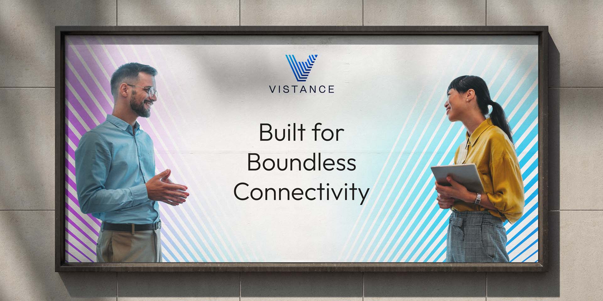 Two people stand facing each other and smiling in front of a billboard that reads “Built for Boundless Connectivity” with the Vistance logo above the text.