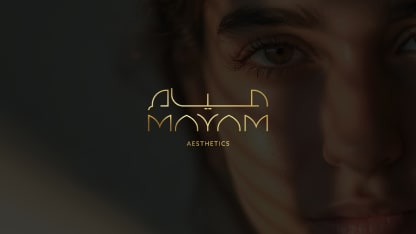 Close-up of a person’s face with soft lighting and shadow, overlaid with the gold logo text “Alya Moyam Aesthetics” in the center.