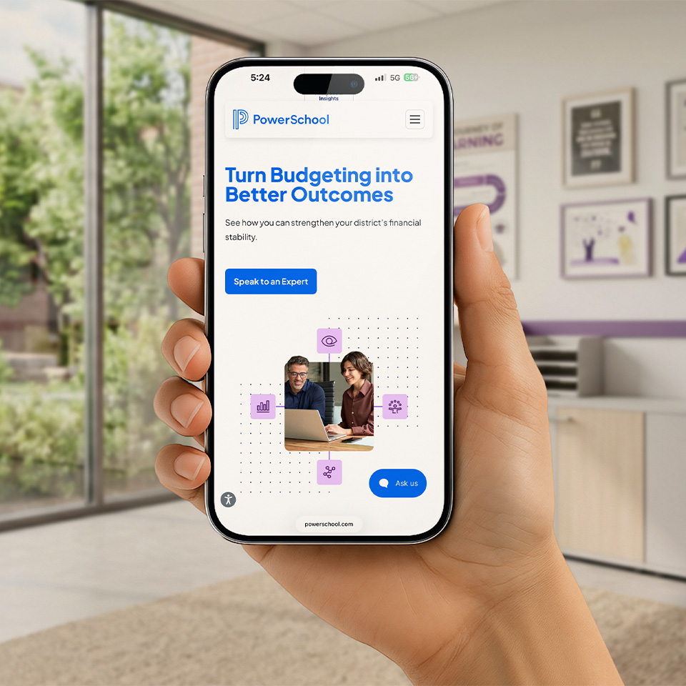 Hand holding a phone showing PowerSchool’s mobile site: “Turn Budgeting into Better Outcomes” with a Speak to an Expert button.