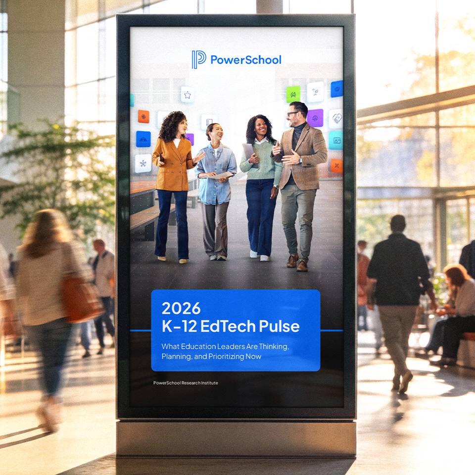 PowerSchool “2026 K-12 EdTech Pulse” poster on a digital kiosk, showing four educators walking and talking.